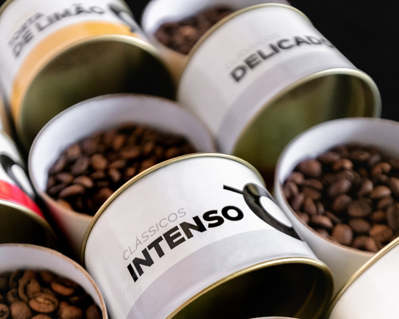 Foto em close de latinhas de cafés da Crio, com destaque para latinhas com o rótulo Intenso e Delicado