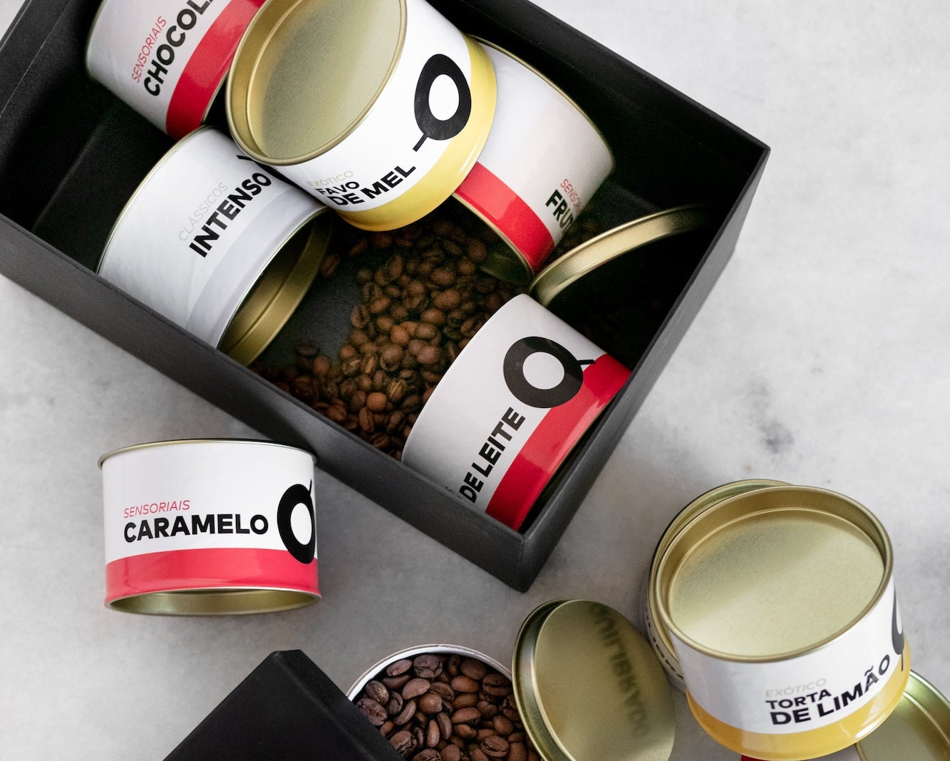 Foto de uma caixa, sobre uma mesa, com várias latas de cafés da Crio. 