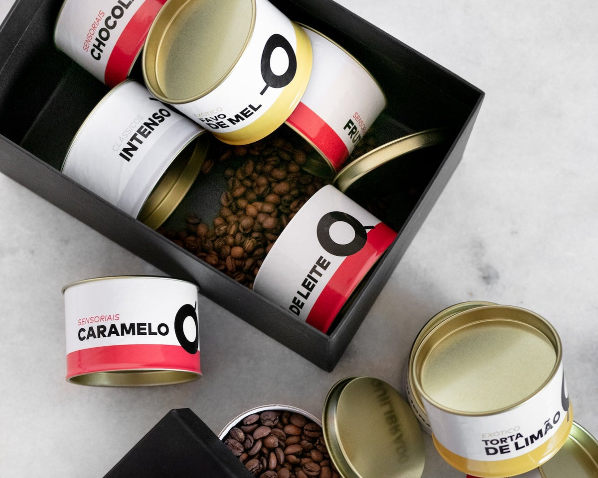 Foto de uma caixa, sobre uma mesa, com várias latas de cafés da Crio. 